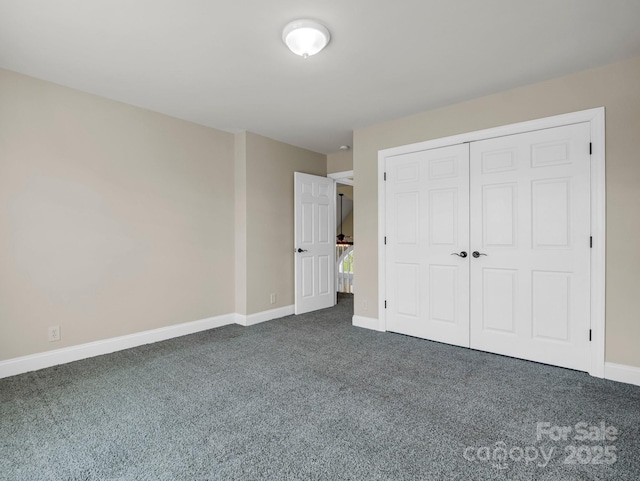 unfurnished bedroom featuring baseboards, dark carpet, and a closet