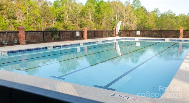 pool with fence and a view of trees