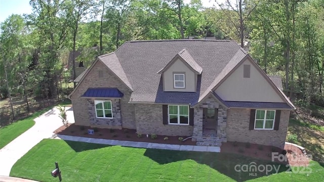 view of front facade featuring a front lawn, driveway, brick siding, and stone siding