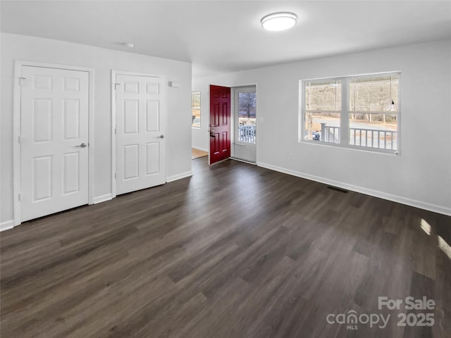 spare room featuring dark wood finished floors, visible vents, and baseboards