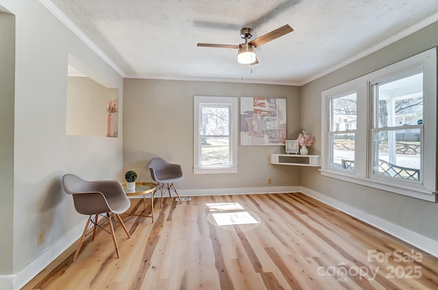 living area with ceiling fan, baseboards, wood finished floors, and ornamental molding