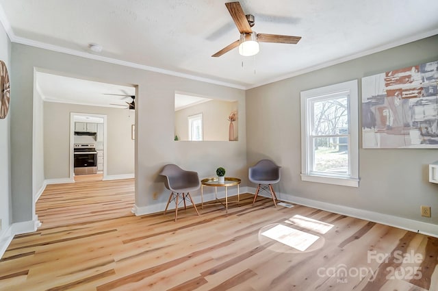 sitting room featuring baseboards, wood finished floors, ceiling fan, and ornamental molding