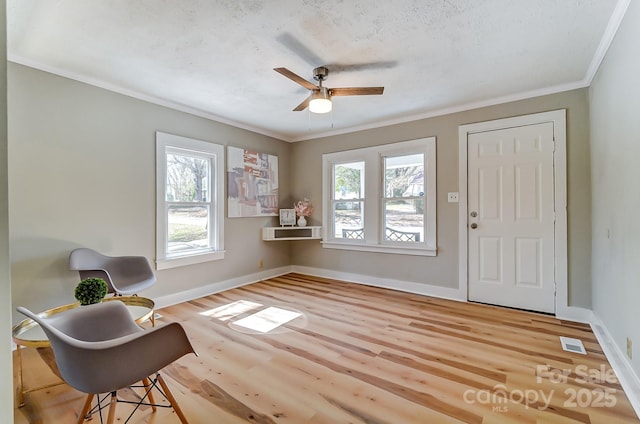 living area featuring a ceiling fan, wood finished floors, baseboards, and ornamental molding