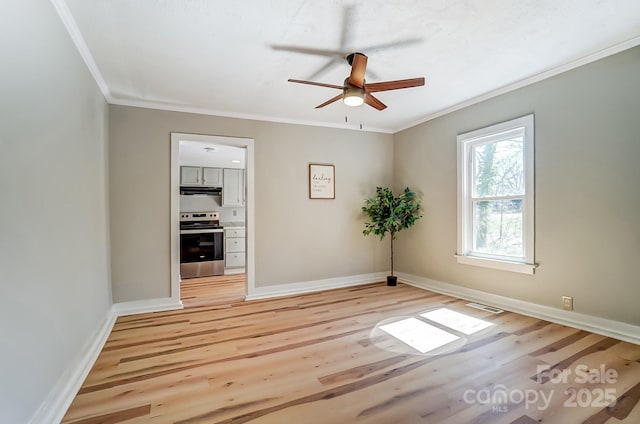 empty room with light wood finished floors, visible vents, crown molding, and baseboards