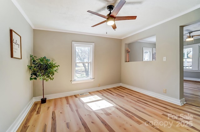 spare room with crown molding, plenty of natural light, and wood finished floors