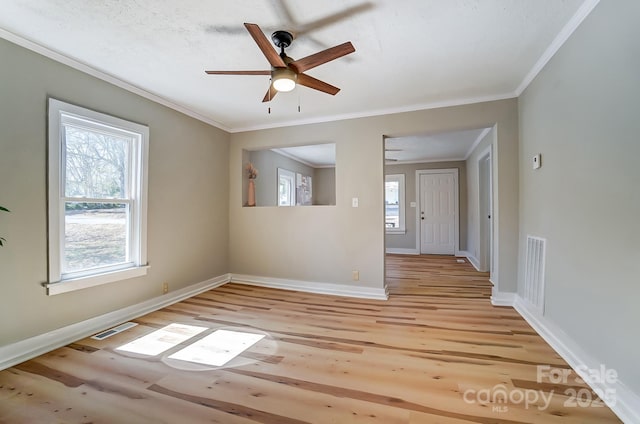 unfurnished room with visible vents, light wood-style floors, and ornamental molding