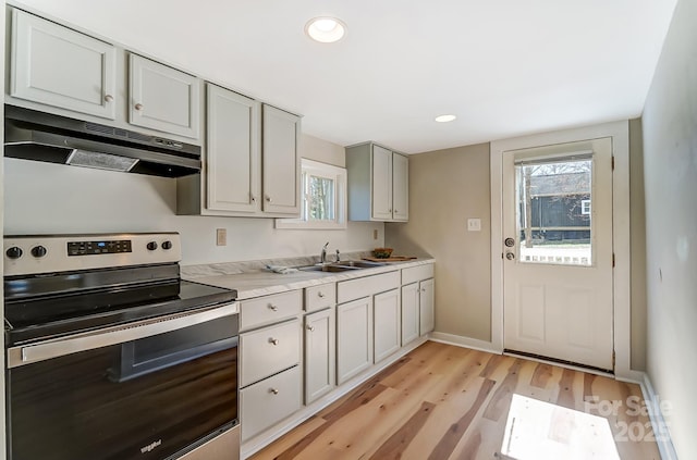 kitchen with stainless steel electric range oven, plenty of natural light, under cabinet range hood, and a sink