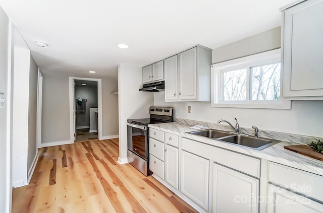 kitchen with under cabinet range hood, stainless steel range with electric cooktop, light countertops, and a sink