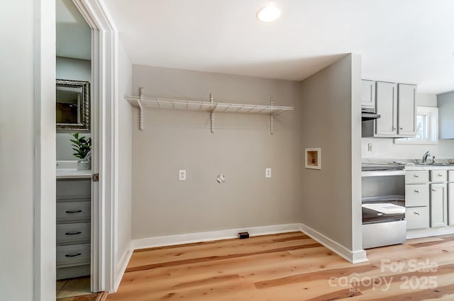 laundry area featuring baseboards, light wood-style floors, and hookup for a washing machine