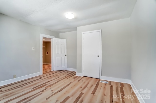 unfurnished bedroom featuring visible vents, wood finished floors, and baseboards