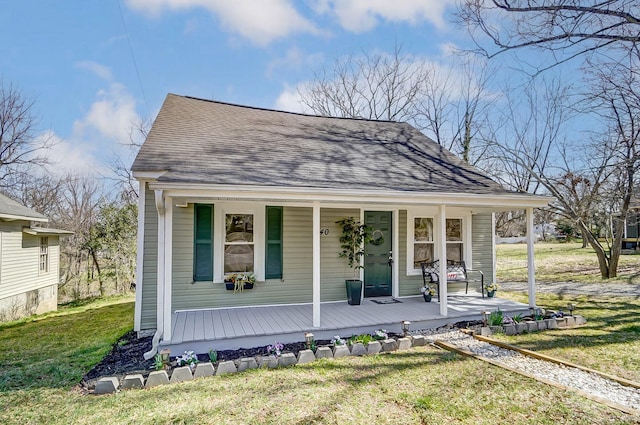 view of front of home featuring roof with shingles, covered porch, and a front lawn