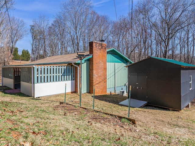 view of side of home with a lawn, a chimney, and a sunroom