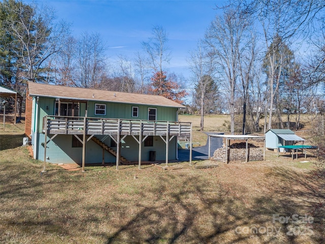 rear view of property featuring a yard, a storage unit, an outdoor structure, and a wooden deck