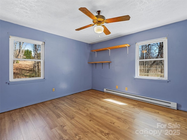 spare room featuring a textured ceiling, a baseboard radiator, and light wood-style floors