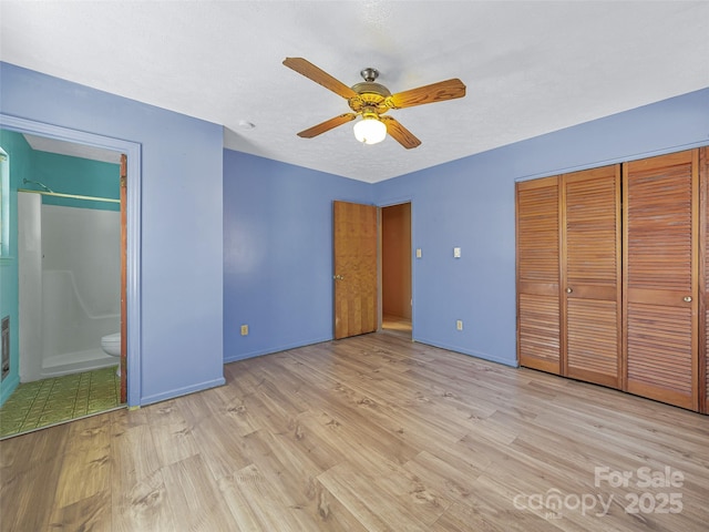 unfurnished bedroom with ensuite bathroom, a closet, light wood-style flooring, and baseboards