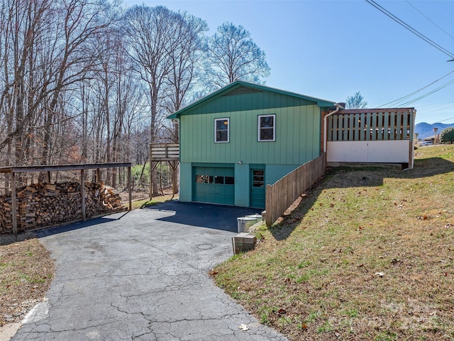 view of property exterior featuring a garage, driveway, a lawn, and a sunroom