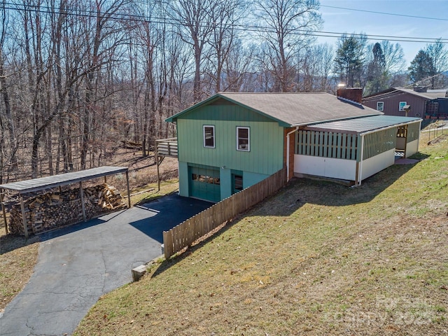 exterior space with a garage, a sunroom, aphalt driveway, and a front yard