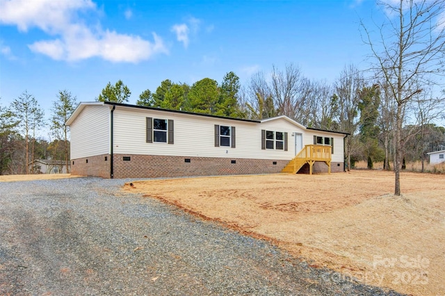 manufactured / mobile home featuring crawl space, stairway, and gravel driveway