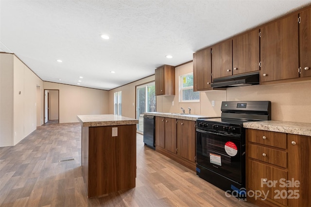 kitchen with a center island, light wood finished floors, light countertops, black range, and under cabinet range hood