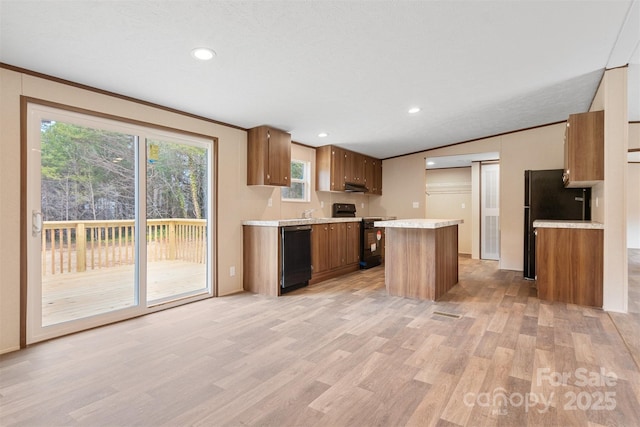 kitchen with light wood-style flooring, brown cabinets, a center island, light countertops, and black appliances