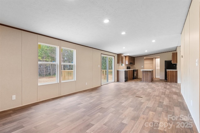 unfurnished living room featuring light wood-style flooring, a textured ceiling, and recessed lighting