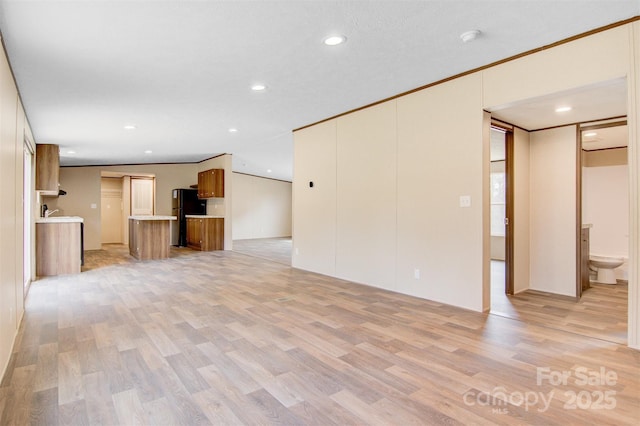 unfurnished living room with ornamental molding, light wood-style flooring, and recessed lighting