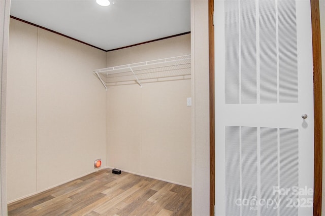 clothes washing area with light wood finished floors, ornamental molding, and a heating unit