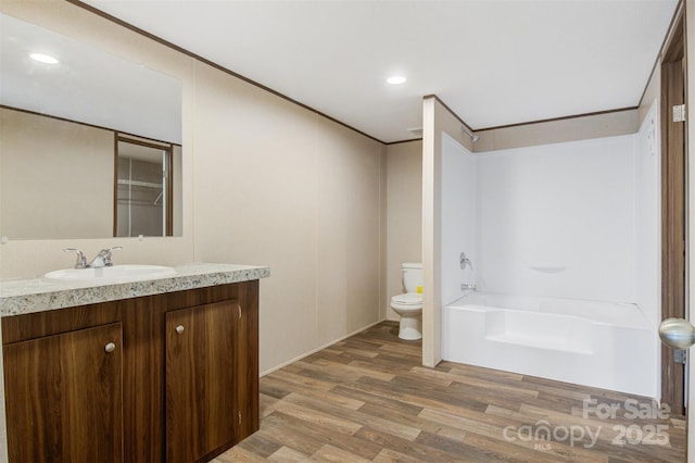 bathroom featuring vanity, ornamental molding, wood finished floors, and toilet