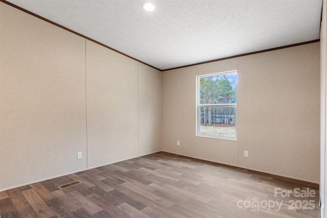 unfurnished room with ornamental molding, visible vents, a textured ceiling, and wood finished floors