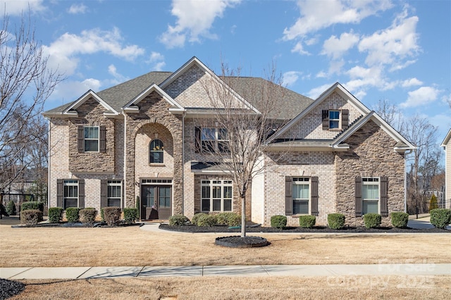 craftsman-style house featuring french doors, brick siding, a front lawn, and a shingled roof