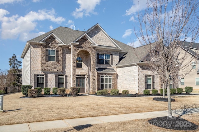 view of front of home featuring brick siding, a shingled roof, and a front yard