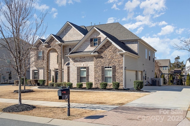 view of front of home with stone siding, driveway, an attached garage, and central AC unit