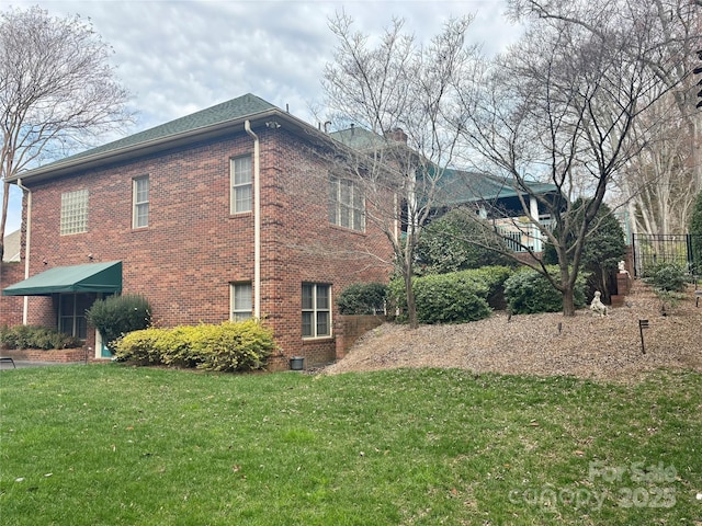 view of side of property featuring brick siding and a yard