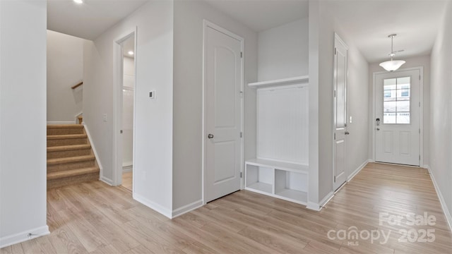 entrance foyer with light wood-style floors, baseboards, and stairway