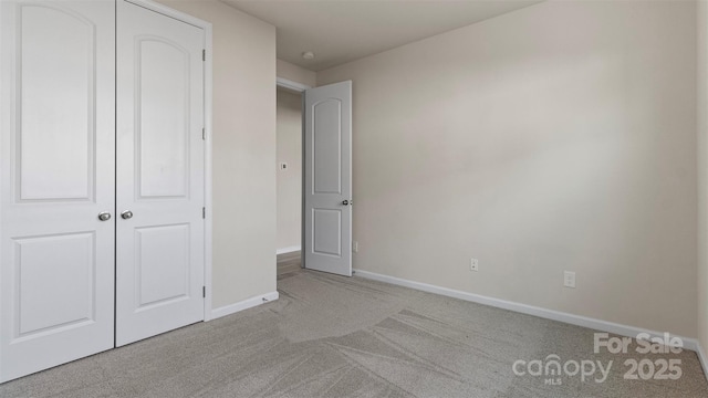 unfurnished bedroom featuring baseboards, a closet, and light colored carpet