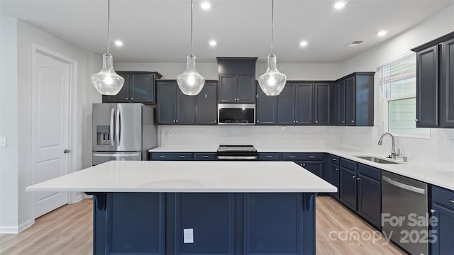 kitchen with stainless steel appliances, a kitchen breakfast bar, hanging light fixtures, light countertops, and a center island