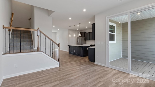 kitchen with a kitchen island, decorative light fixtures, freestanding refrigerator, light countertops, and light wood-style floors