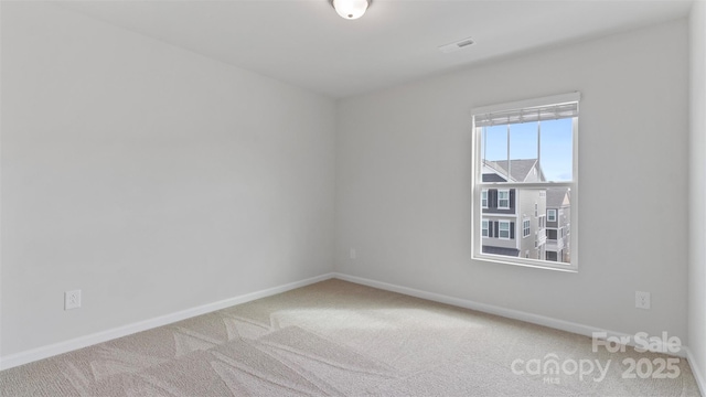 empty room with carpet, visible vents, and baseboards