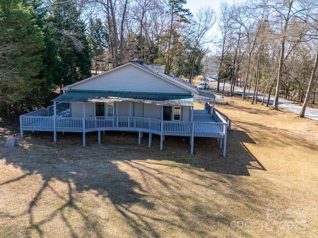 view of front of home with metal roof, a wooden deck, and dirt driveway