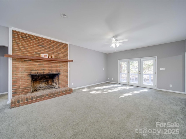 unfurnished living room with carpet floors, a brick fireplace, french doors, and baseboards