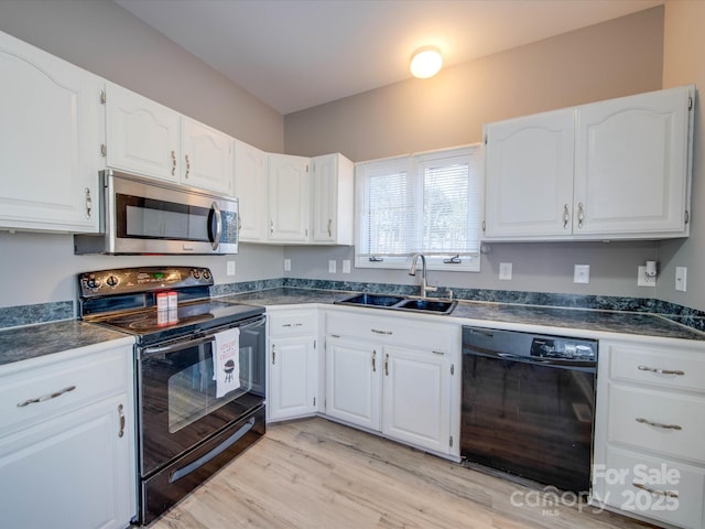 kitchen featuring black appliances, dark countertops, a sink, and white cabinetry