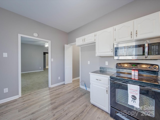 kitchen with light wood finished floors, stainless steel microwave, white cabinets, black range with electric cooktop, and baseboards