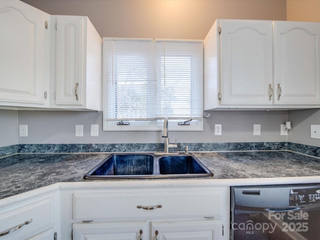 kitchen featuring dishwashing machine, dark countertops, a sink, and white cabinets