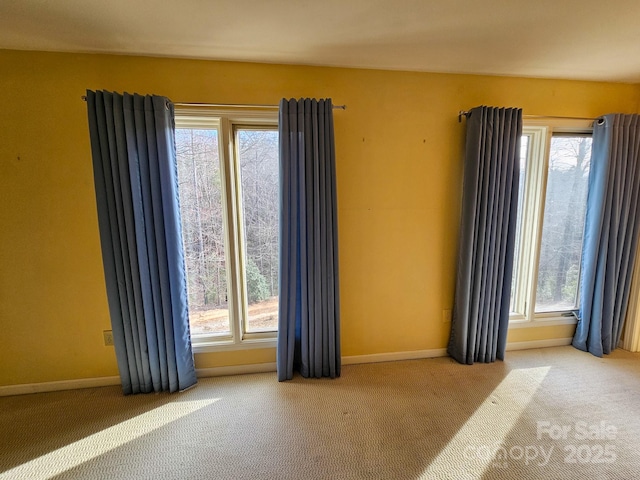 unfurnished room with plenty of natural light, light colored carpet, and baseboards