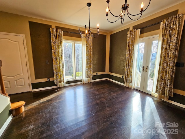 unfurnished dining area featuring dark wood-style floors, french doors, a healthy amount of sunlight, and an inviting chandelier