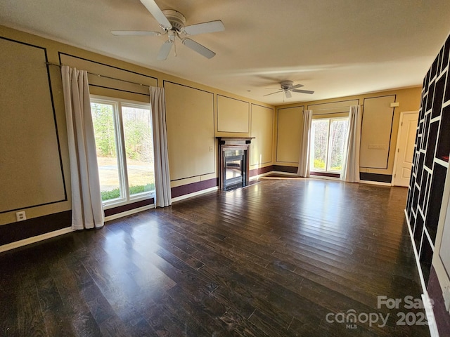 unfurnished living room with dark wood-style floors, a fireplace, and a ceiling fan