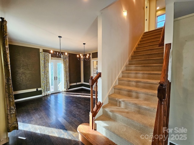 stairway featuring a notable chandelier, ornamental molding, wood finished floors, and french doors