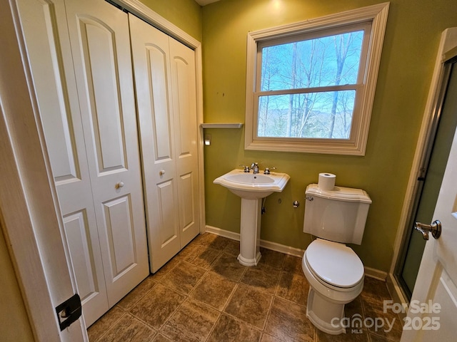 full bath with toilet, a sink, baseboards, and a closet