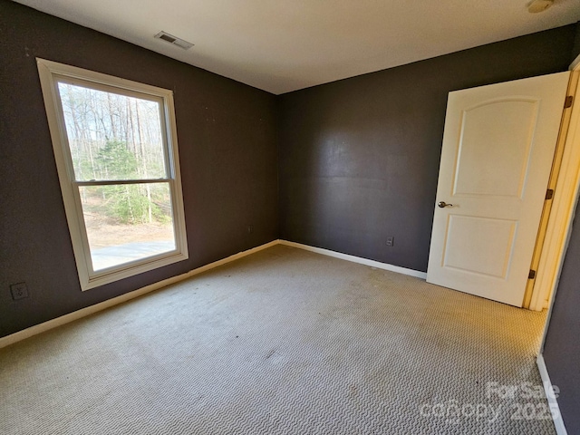 empty room with carpet floors, visible vents, and baseboards