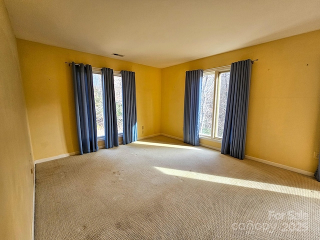 unfurnished room with carpet floors, visible vents, and baseboards